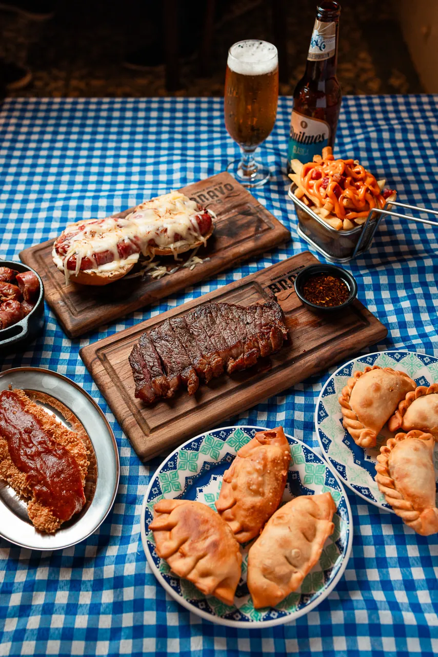 Mesa do Bravo Parrilla com carnes, empanadas, batata e bebidas